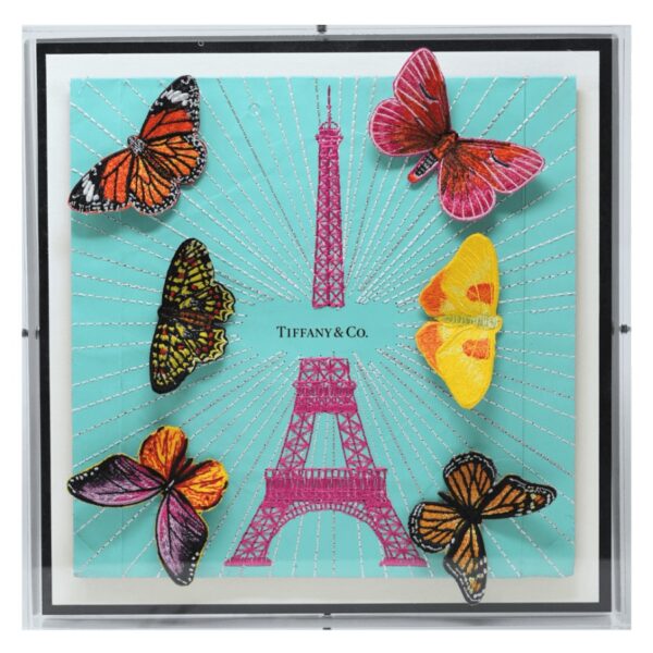 The 12” x 12" size is created using a single luxury bag or box while the larger sizes are created from luxury boxes and bags that are deconstructed, collaged and then embroidered into one large background. The Eiffel Tower itself is embroidered directly through the background. The embroidered butterflies are added in relief to the tower and are available in either natural or tonal colors.  12" x 12" x 2" in size. The art comes framed in acrylic and is signed and numbered by the artist. 